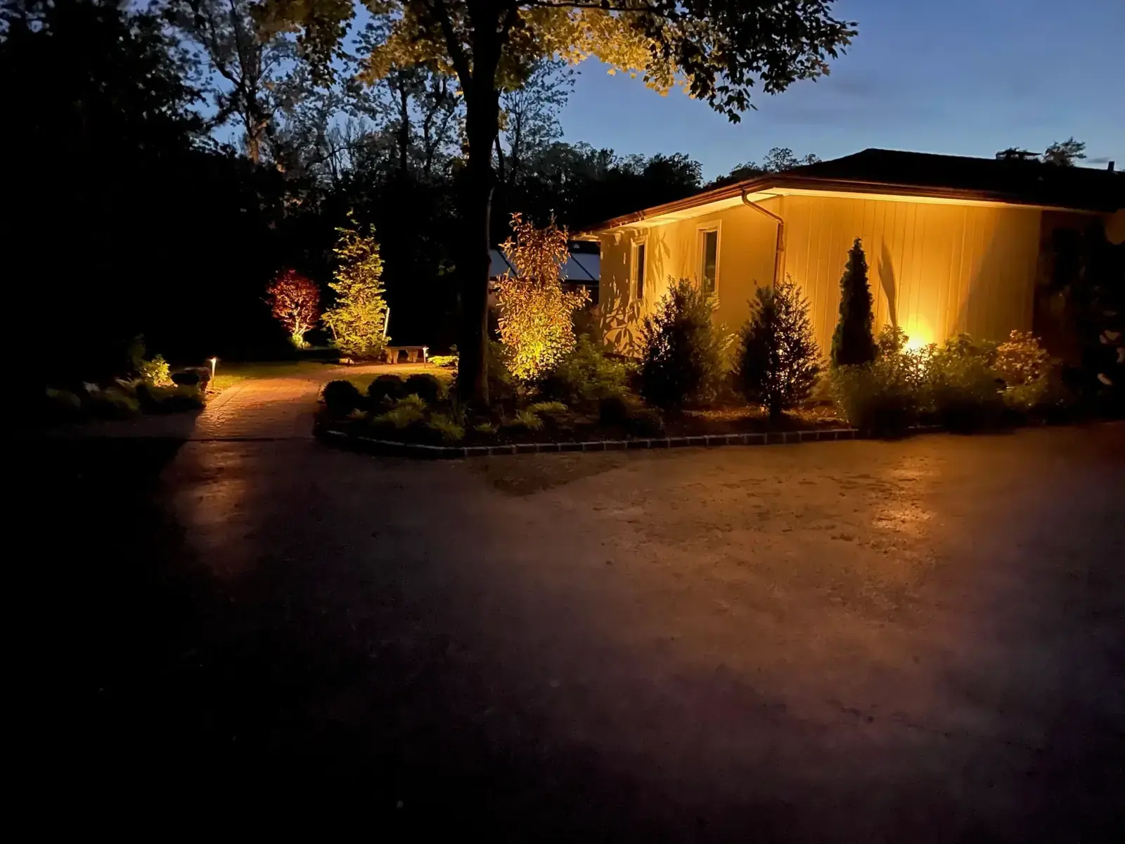 Low voltage outdoor landscape lighting on a home and plantings on Long Island